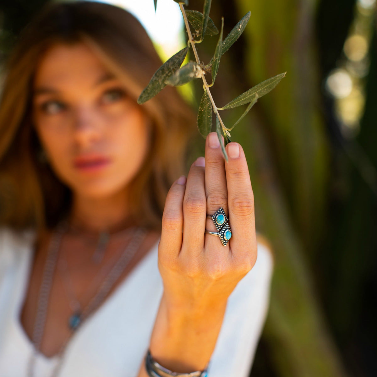 SOWELL JEWELRY Bahman ring featuring two oval turquoise stones on an adjustable sterling silver band on a woman's hand