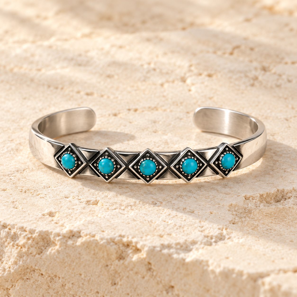 SOWELL JEWELRY Catalina cuff bracelet in sterling silver with five round turquoise stones on a textured stone surface.