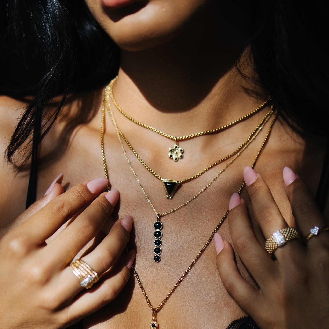 SOWELL JEWELRY 18K gold vermeil flower necklace with onyx stones layered with gold chains on a woman's neck