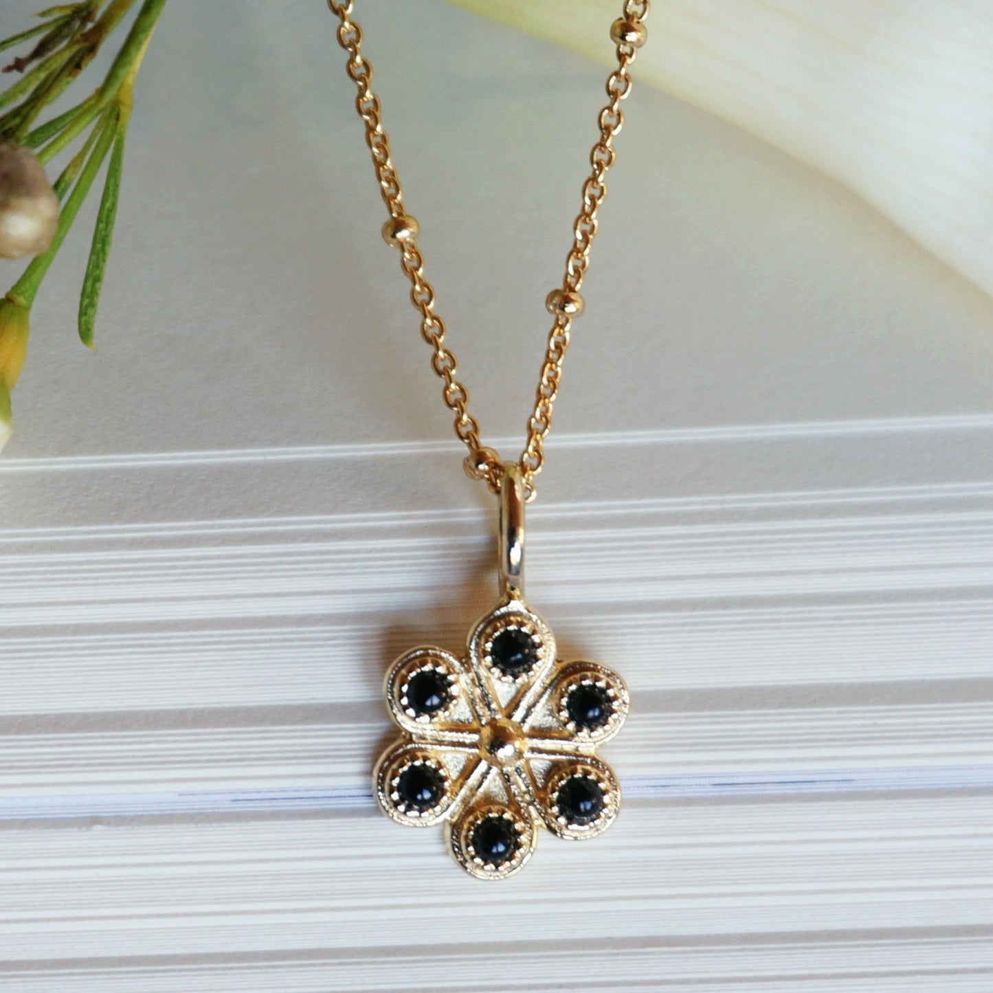SOWELL JEWELRY 18K gold vermeil flower pendant necklace featuring six black onyx stones on a delicate beaded chain.