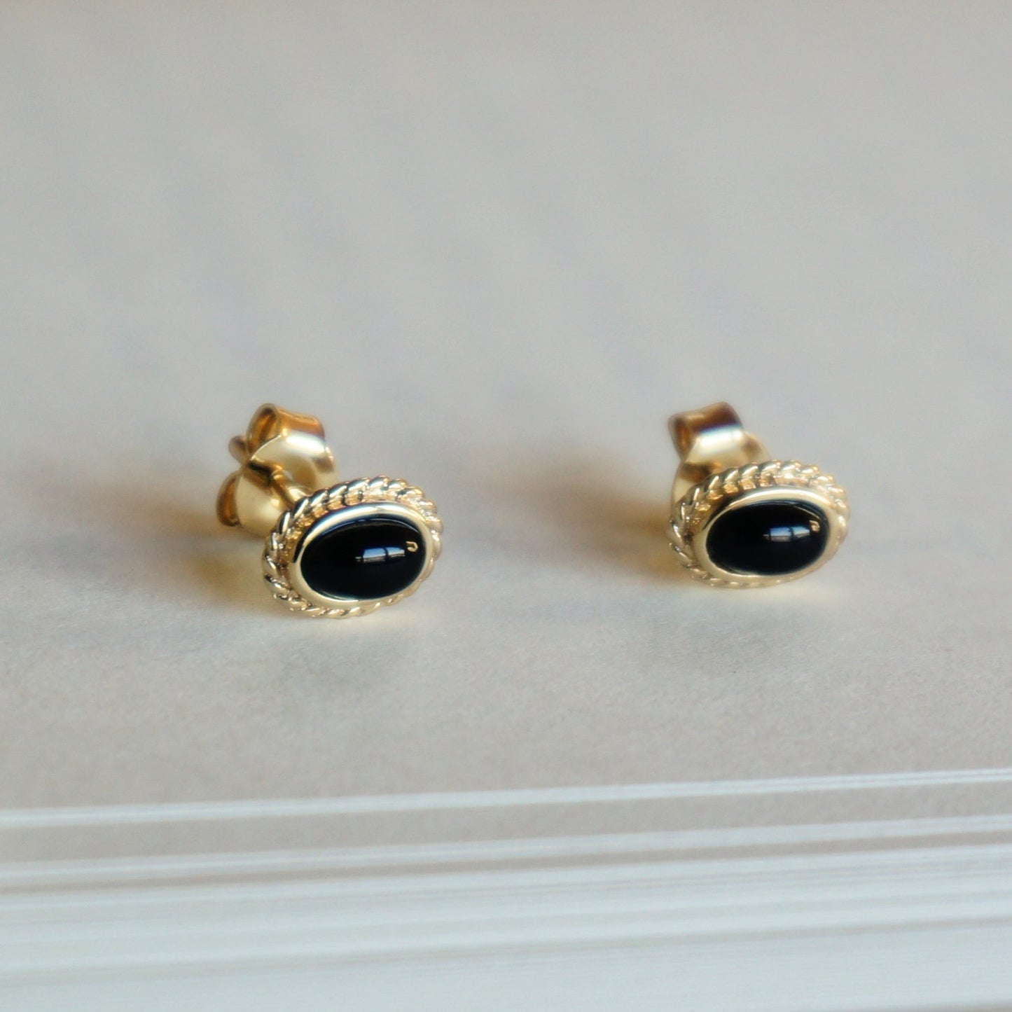 SOWELL JEWELRY 18k gold-plated stud earrings featuring oval black onyx stones with an intricate braided frame.