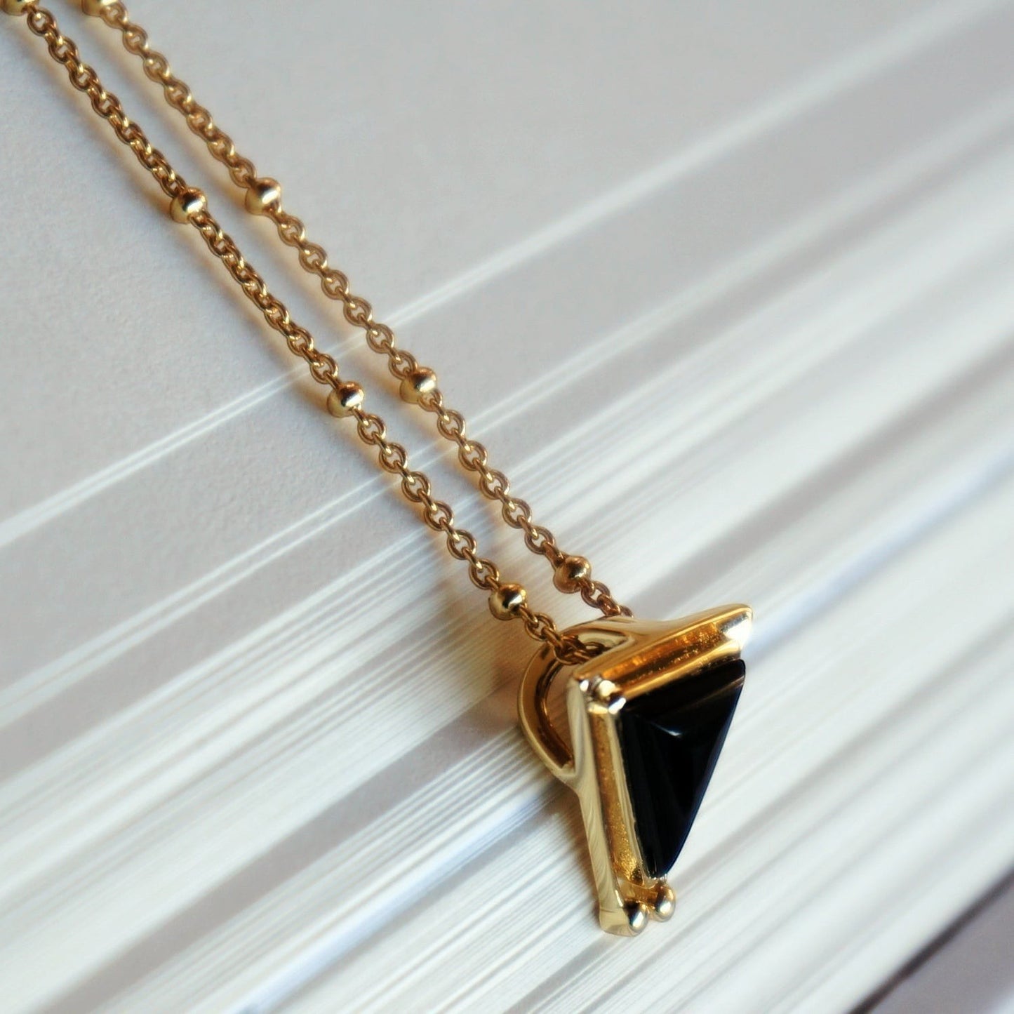 SOWELL JEWELRY 18K gold plated necklace featuring a triangular black onyx pendant on a delicate gold ball chain.