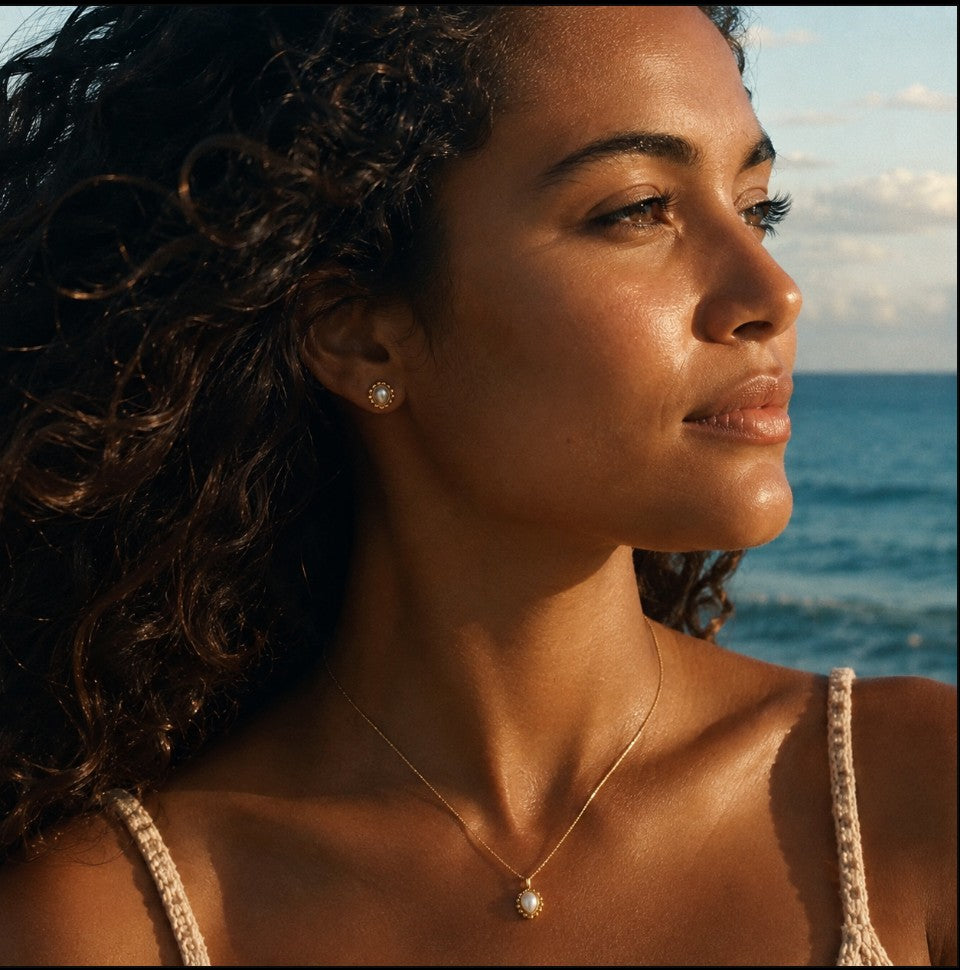 SOWELL JEWELRY Maya teardrop earrings in 18k gold vermeil with iridescent mother of pearl worn by a woman at sunset