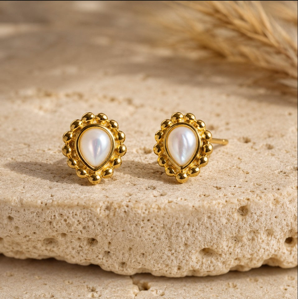 SOWELL JEWELRY Maya teardrop earrings featuring iridescent mother of pearl set in 18k gold vermeil on stone surface.