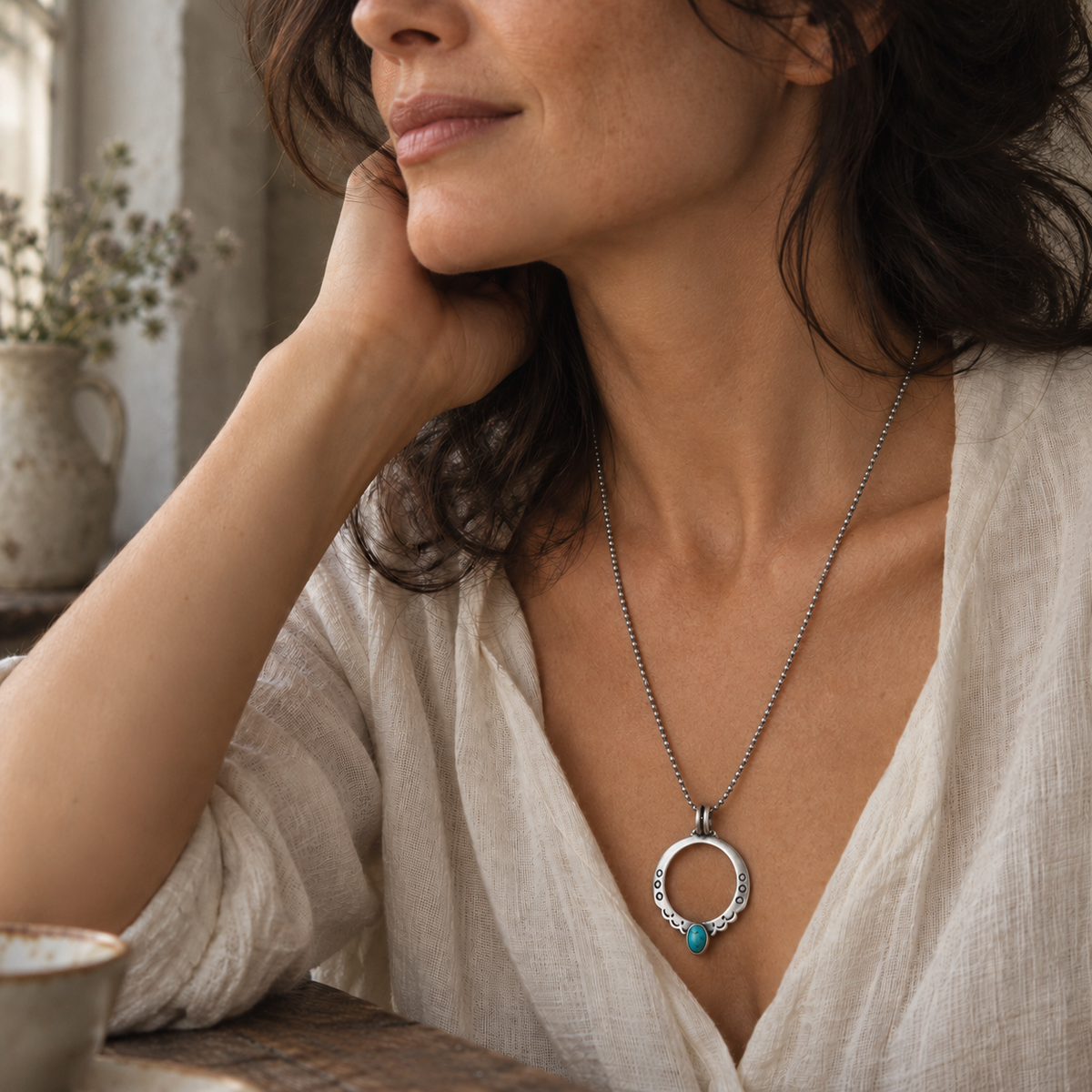 SOWELL JEWELRY Moongate necklace featuring a hammered sterling silver circle pendant with turquoise on a long chain.