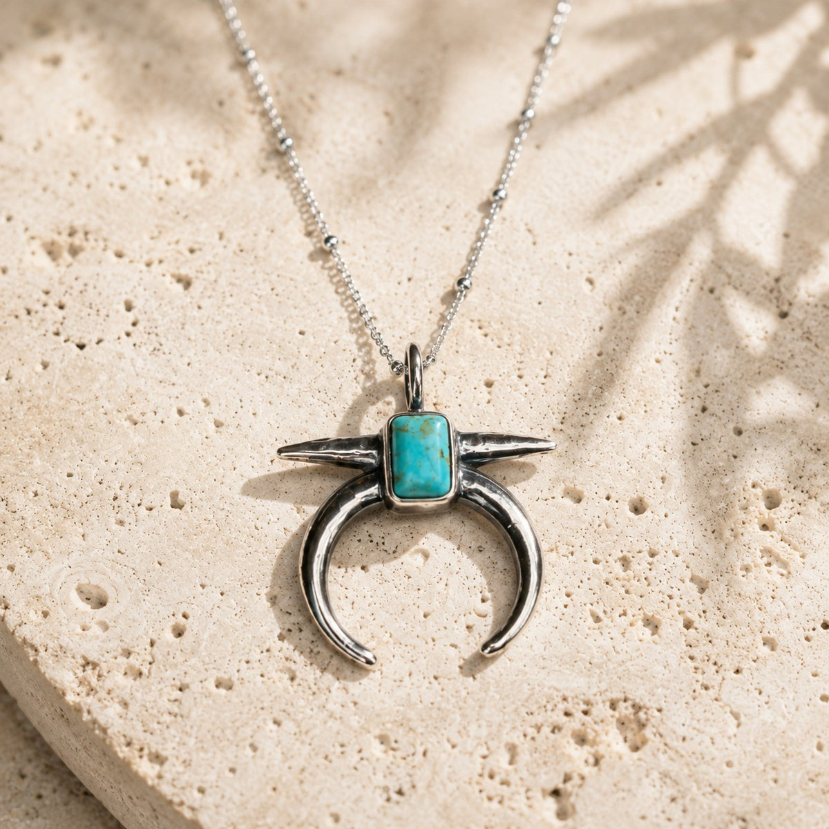 SOWELL JEWELRY Naja crescent pendant necklace with genuine turquoise stone in .925 sterling silver on stone surface