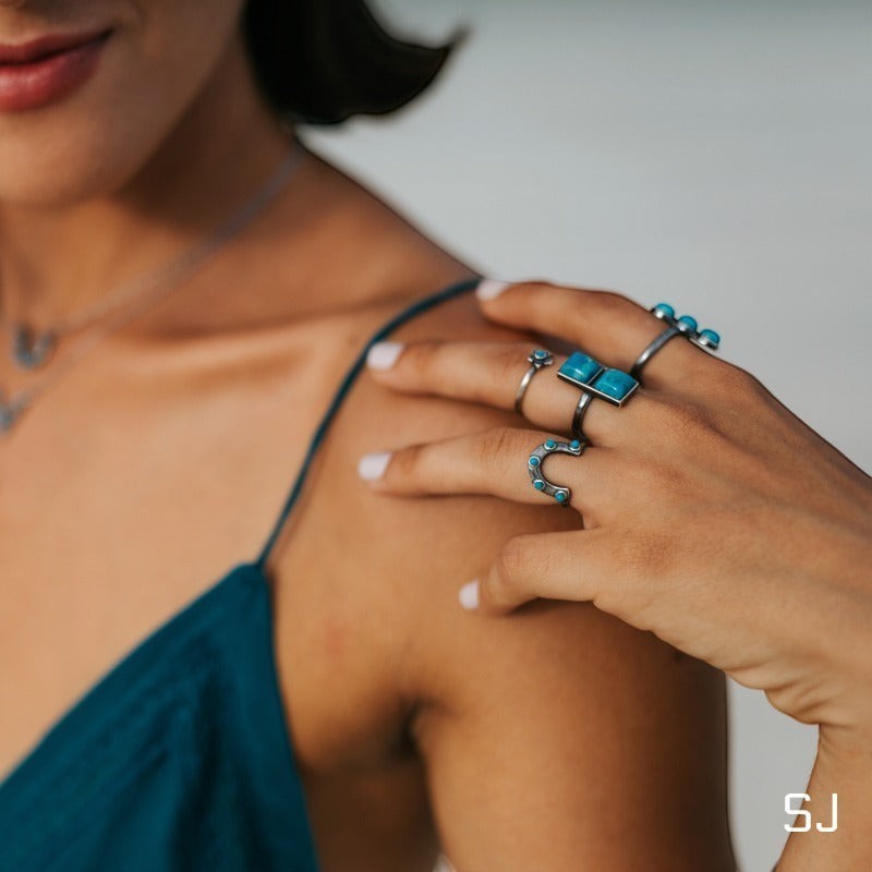 SOWELL JEWELRY sterling silver horseshoe ring with turquoise stone worn on a woman's hand with other rings