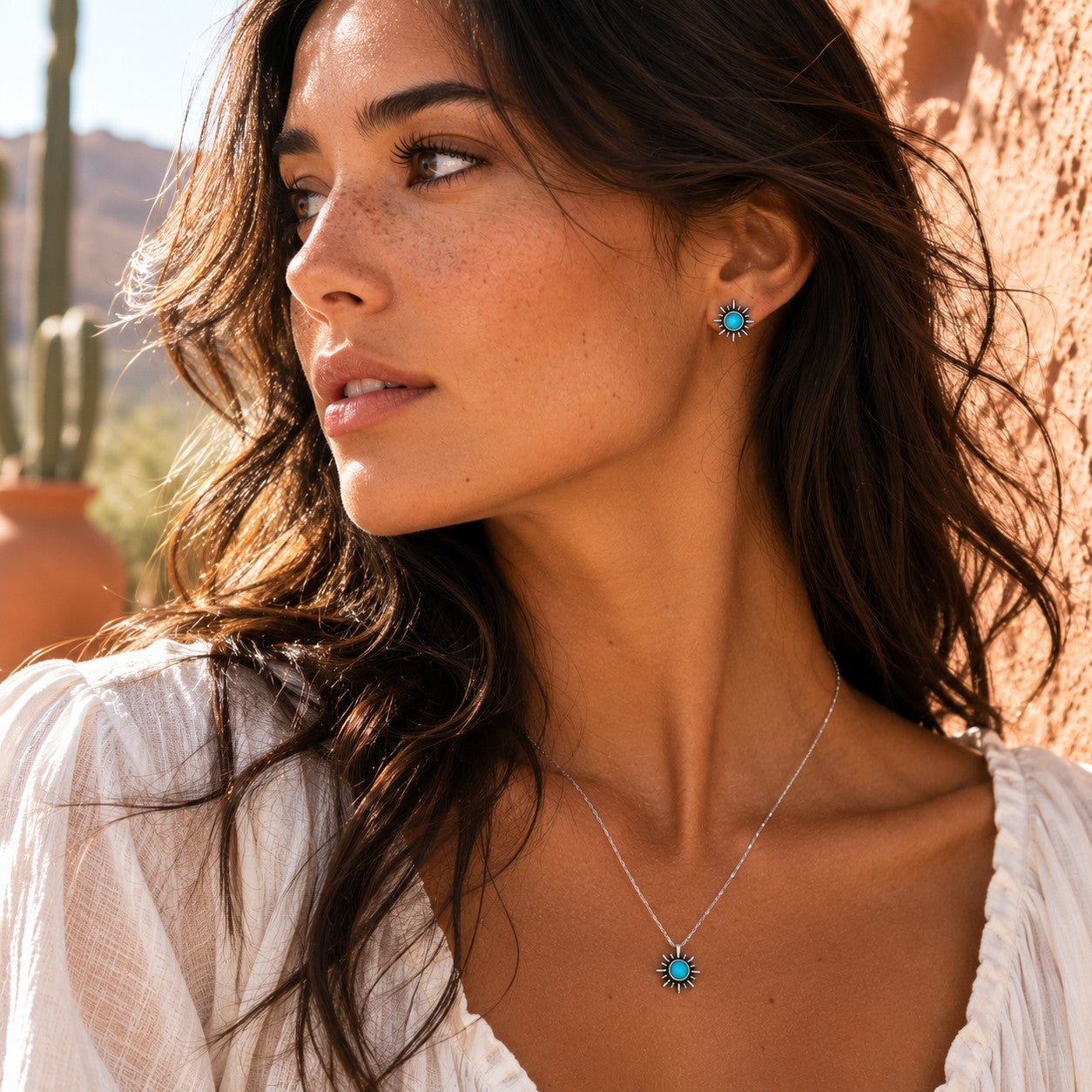 SOWELL JEWELRY sunburst turquoise earrings and matching necklace in sterling silver worn by a woman in a desert setting