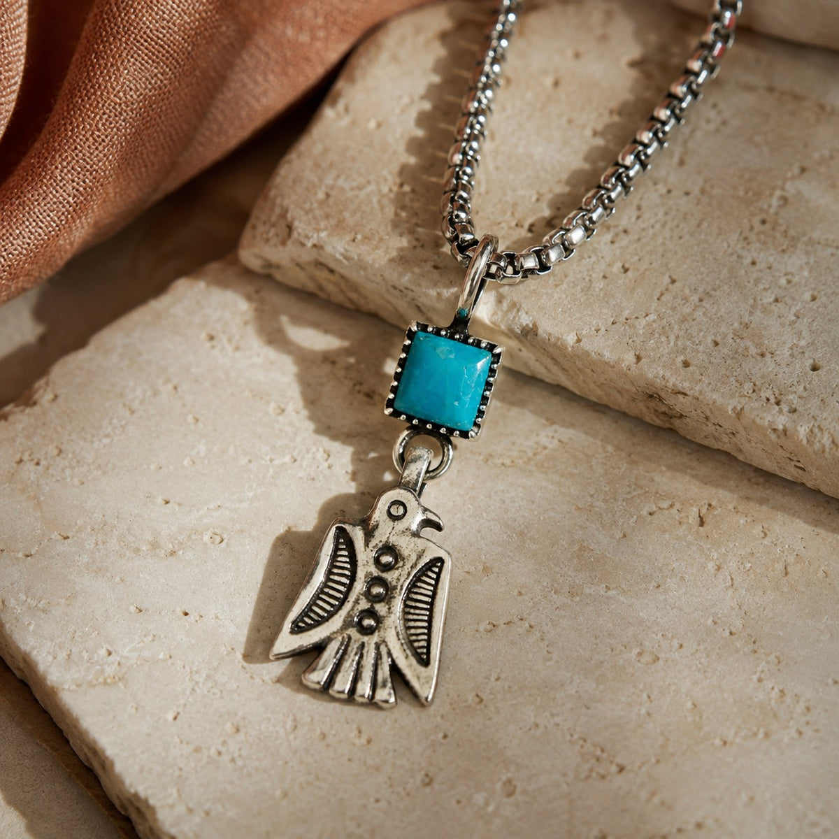 SOWELL JEWELRY sterling silver Thunderbird charm necklace featuring a square turquoise stone on a stainless steel chain