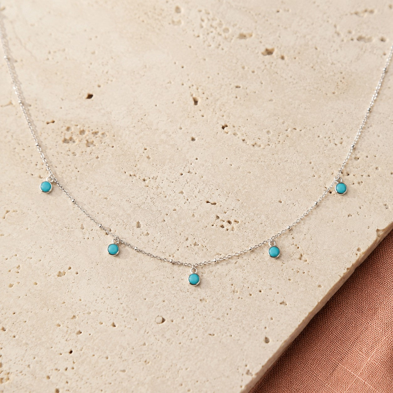 SOWELL JEWELRY delicate silver-tone chain necklace featuring dainty bezel-set turquoise stones and bead accents.