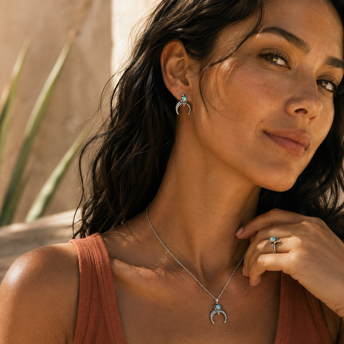 SOWELL JEWELRY Naja turquoise crescent stud earrings in handcrafted sterling silver worn by a woman outdoors
