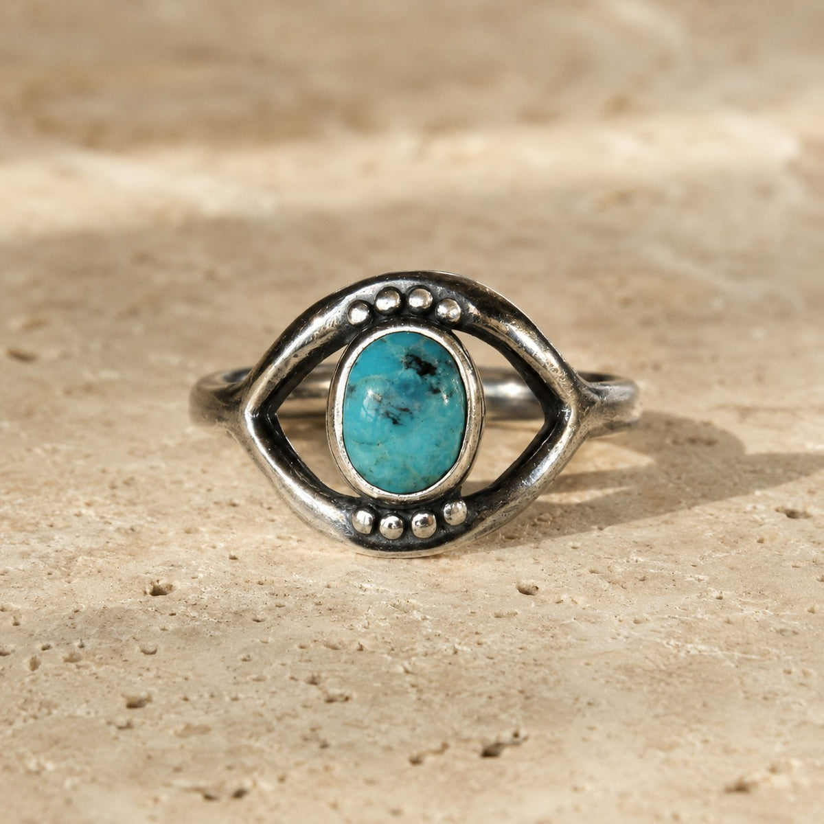 SOWELL JEWELRY sterling silver evil eye ring featuring a genuine turquoise stone on a textured stone surface.