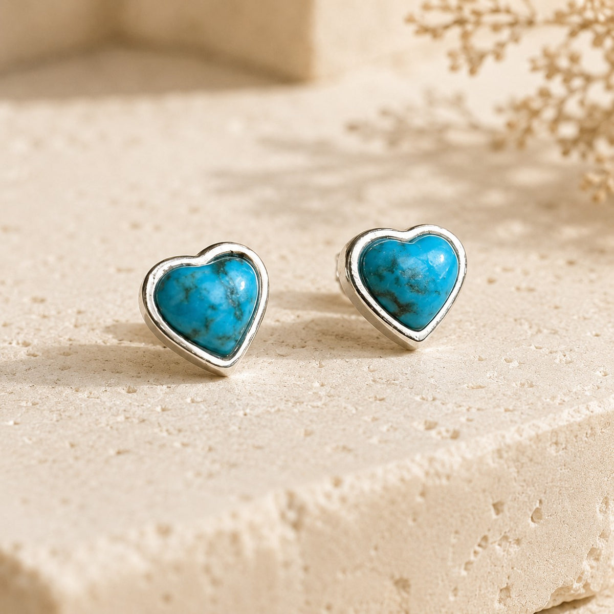 SOWELL JEWELRY turquoise heart stud earrings in .925 sterling silver settings on a textured stone surface