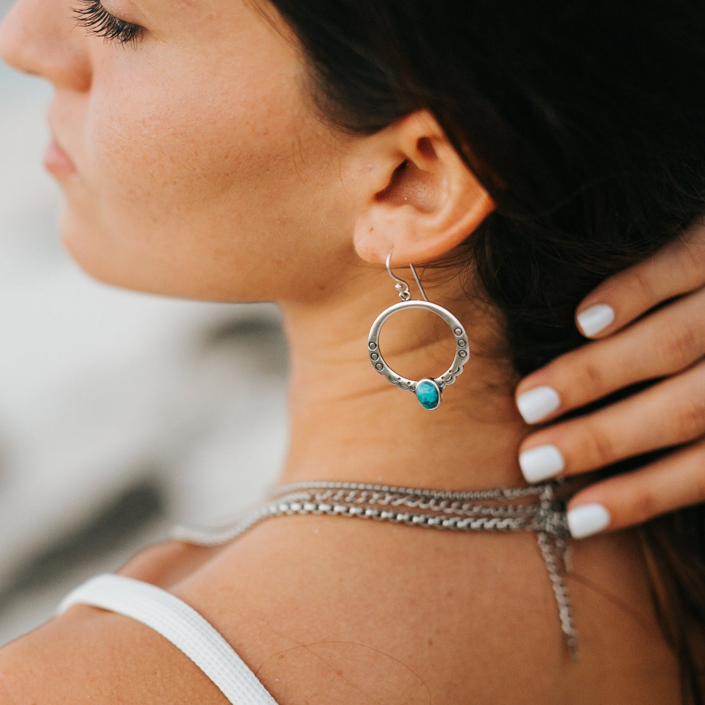 SOWELL JEWELRY Moongate sterling silver hoop earrings featuring an oval turquoise stone worn by a woman