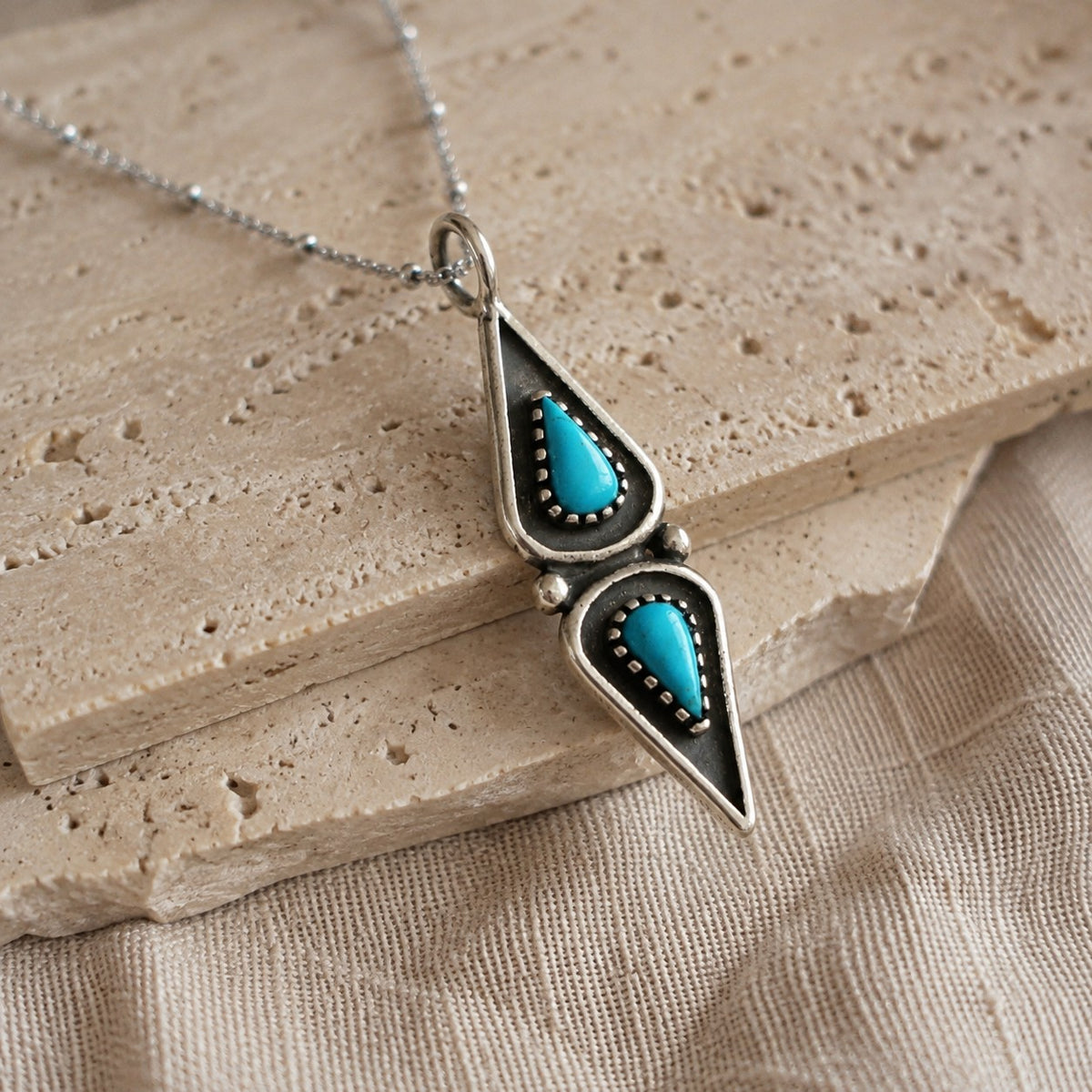 SOWELL JEWELRY Elan pendant necklace featuring two elongated turquoise stones set in oxidized .925 sterling silver.
