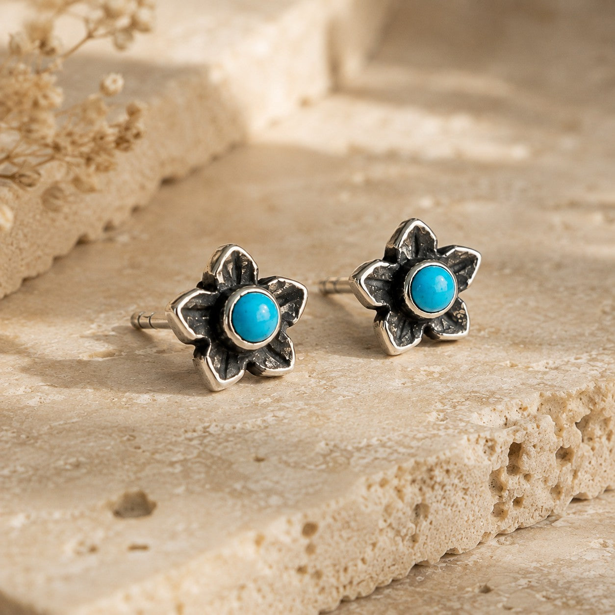 SOWELL JEWELRY turquoise plumeria flower stud earrings in handcrafted .925 sterling silver on a textured stone surface.