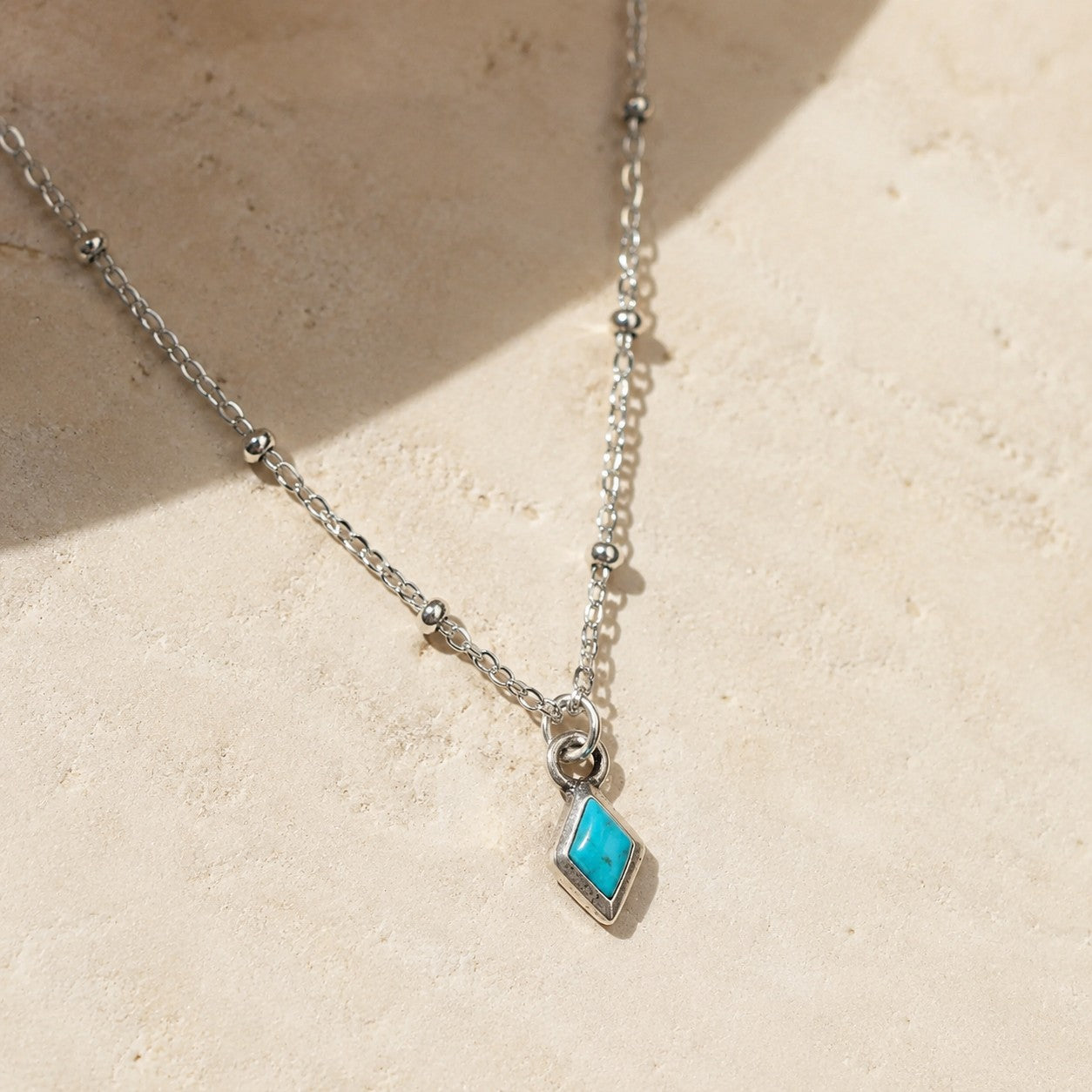 SOWELL JEWELRY delicate sterling silver necklace featuring a small rhombus-shaped turquoise bead on a beaded chain.