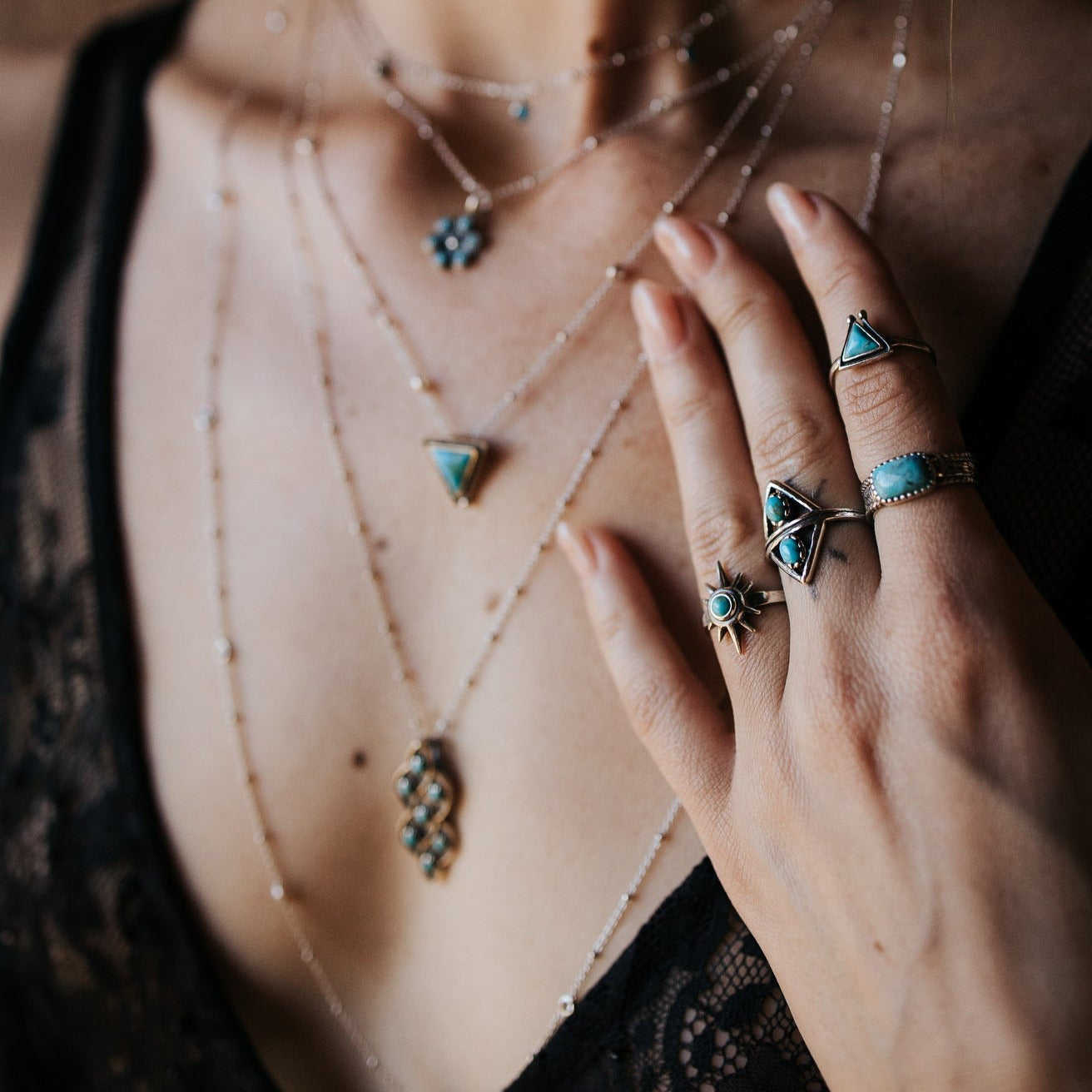 SOWELL JEWELRY sterling silver star ring with turquoise stone worn on a hand with layered necklaces