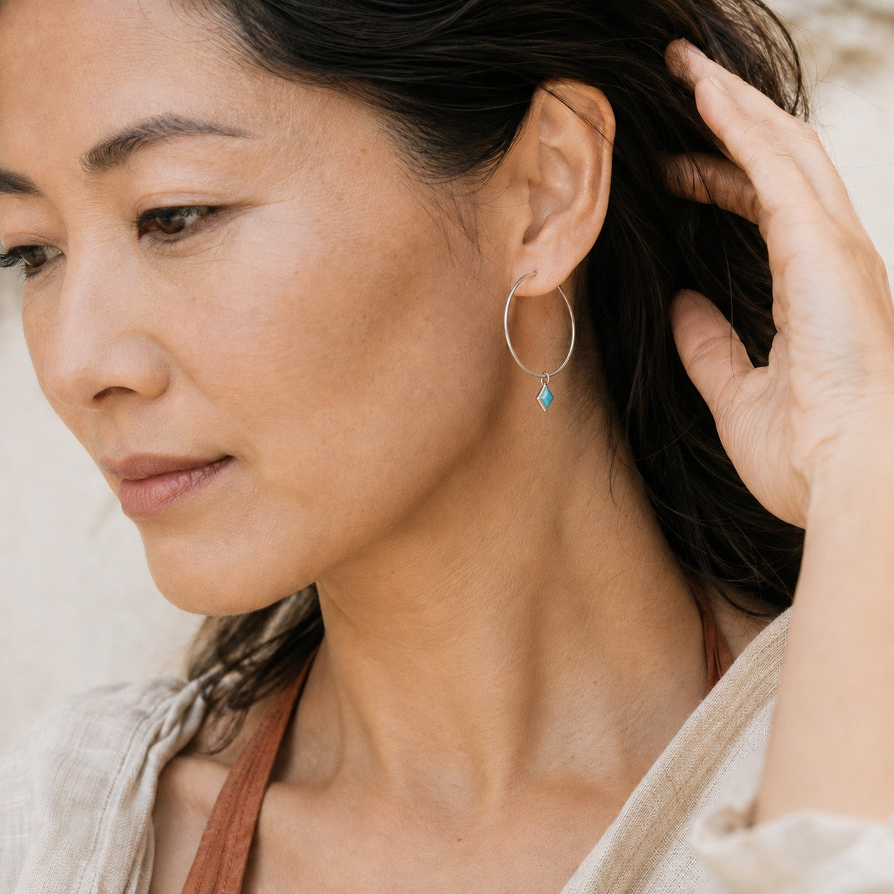 SOWELL JEWELRY Dir turquoise hoop earrings in .925 sterling silver worn by a woman with dark hair